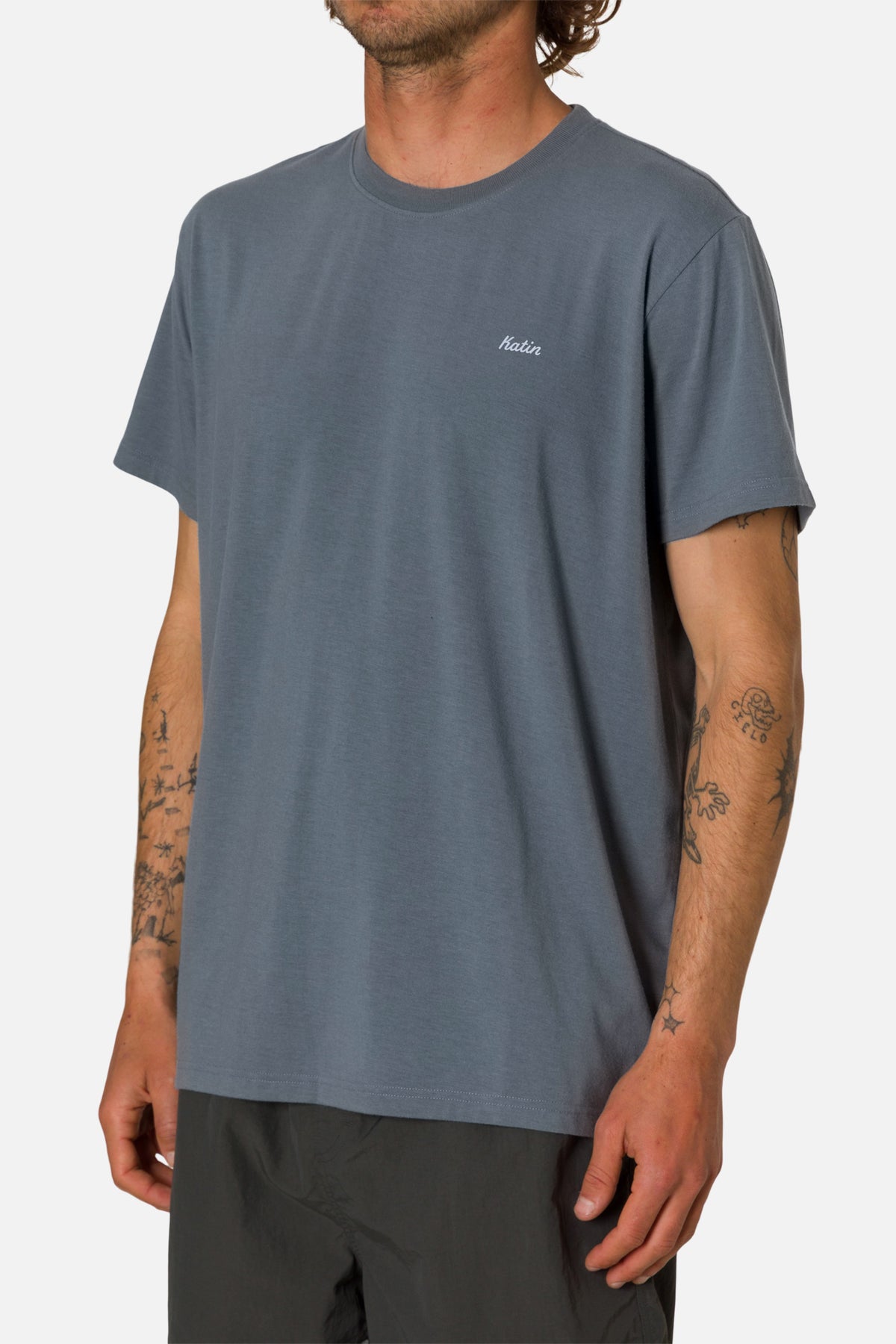 Person wearing a blue t-shirt with a small logo on a white background