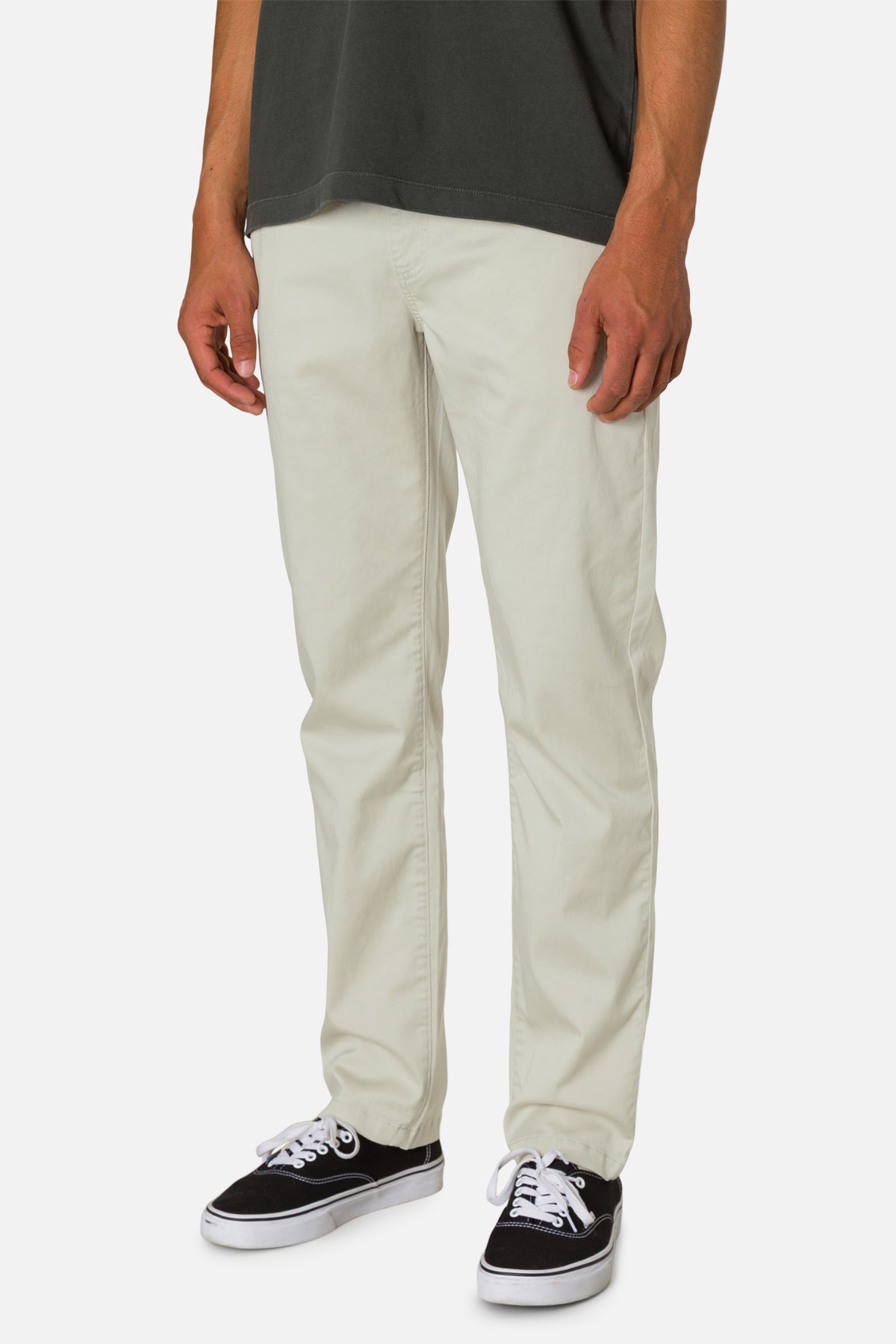 Person wearing light-colored pants and black sneakers on a white background