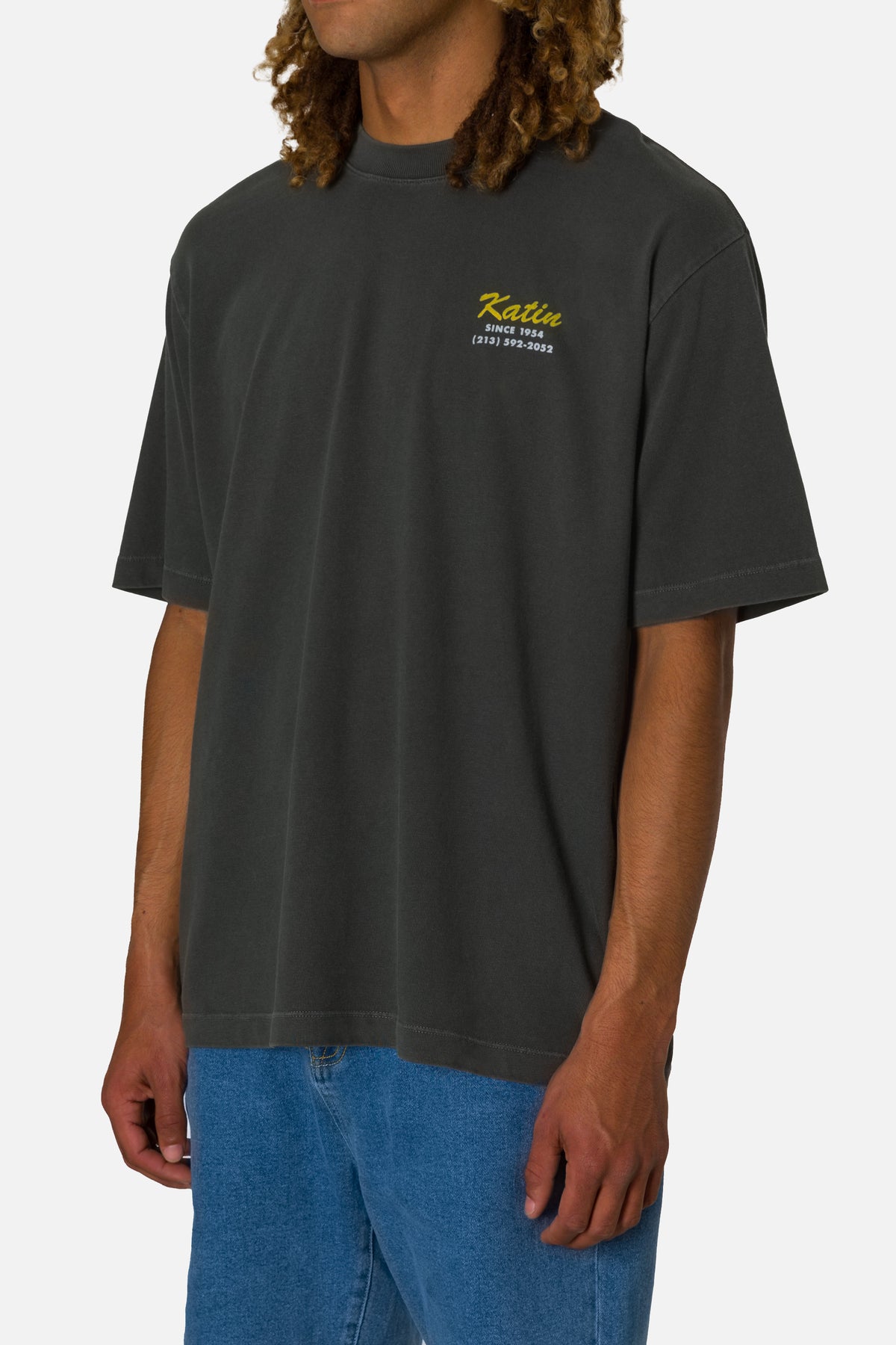 Person wearing a dark gray t-shirt with a logo on a white background
