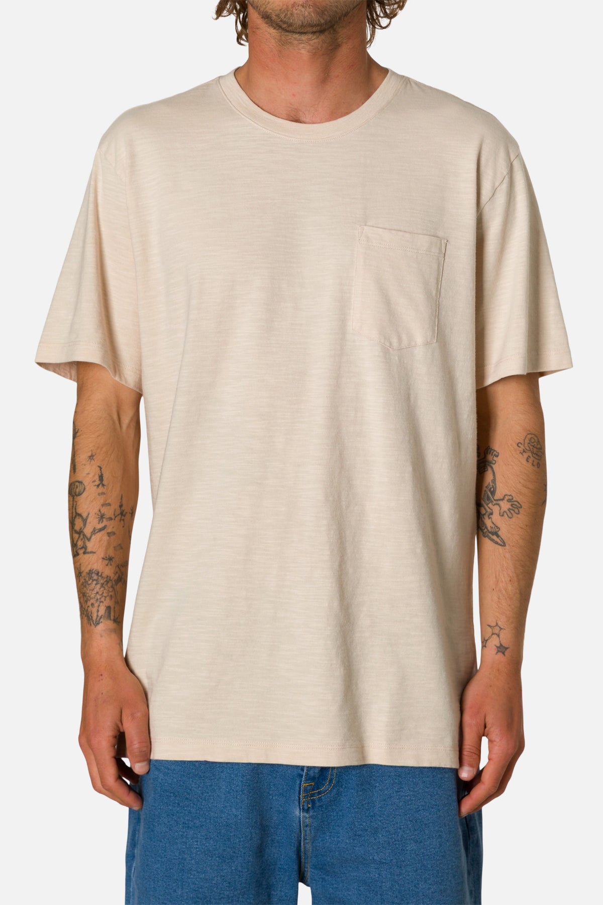 Person wearing a beige t-shirt with a pocket on a white background