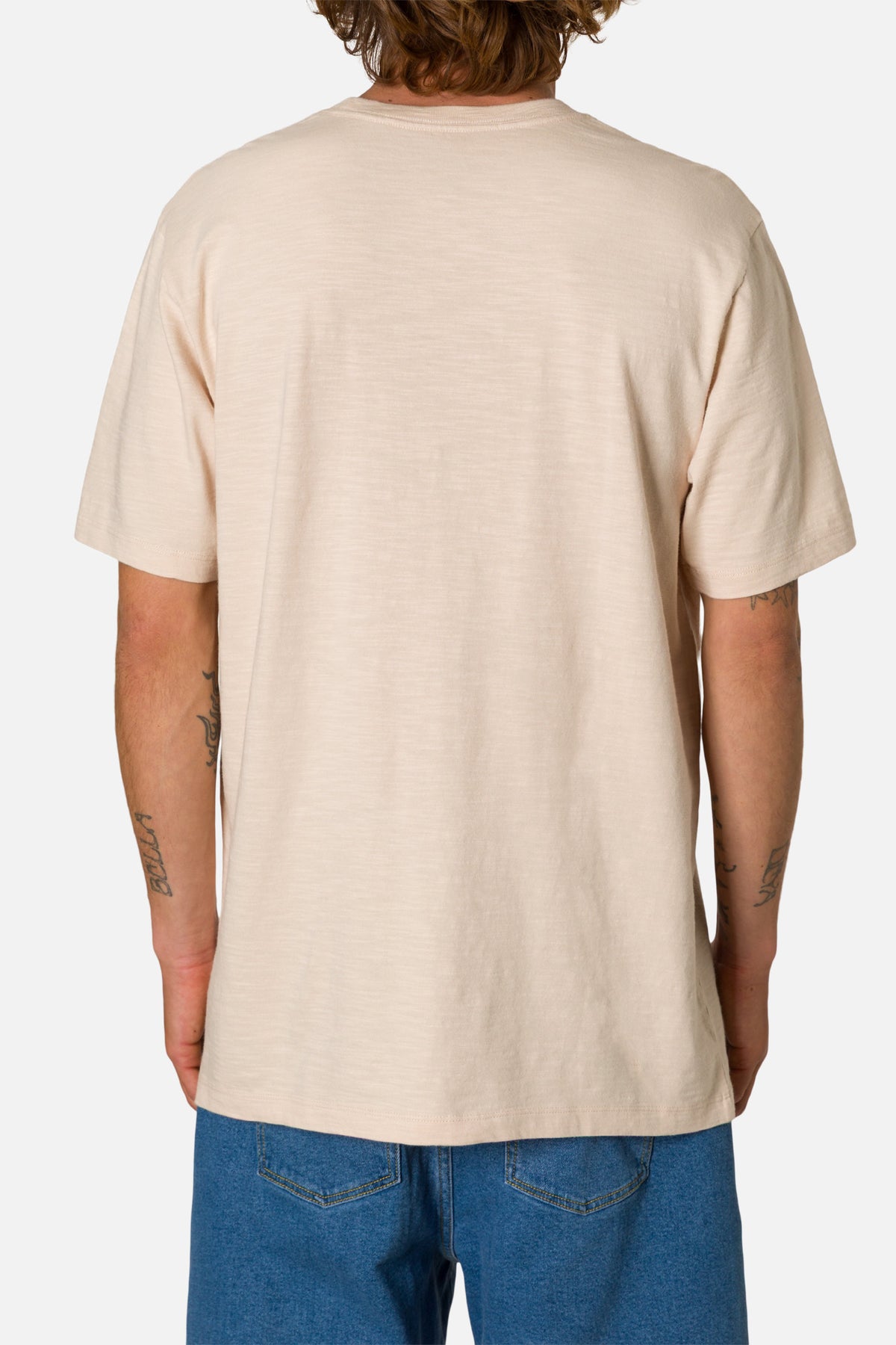 Person wearing a beige t-shirt and blue jeans on a white background