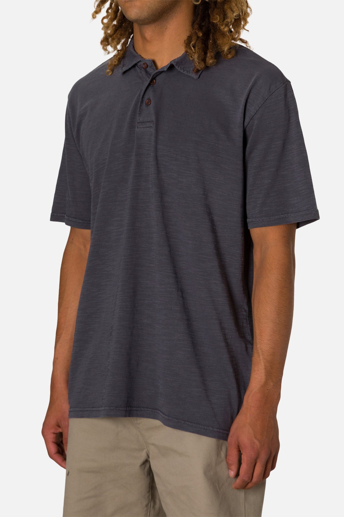 Man wearing a dark blue polo shirt and beige pants on a white background