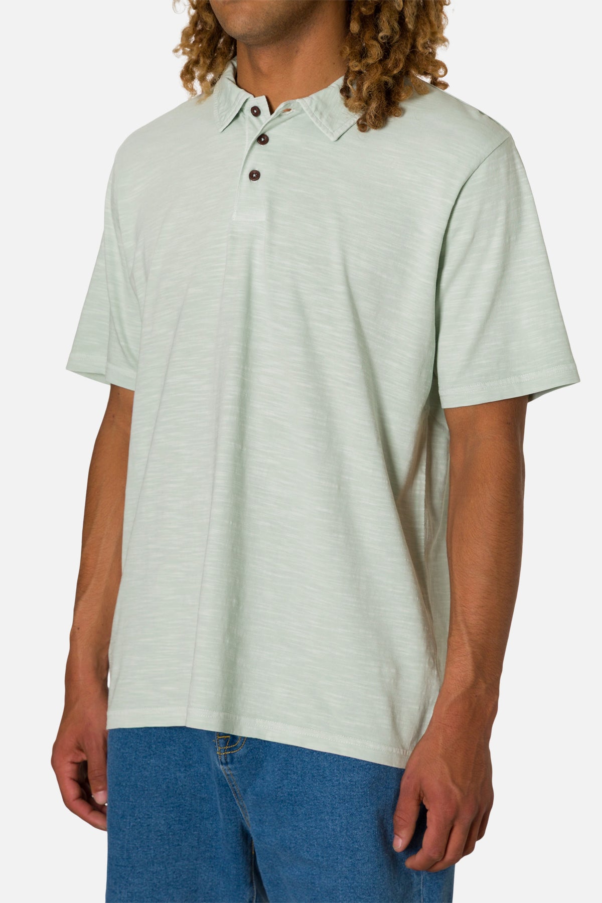 Man wearing a light green polo shirt with brown buttons on a white background