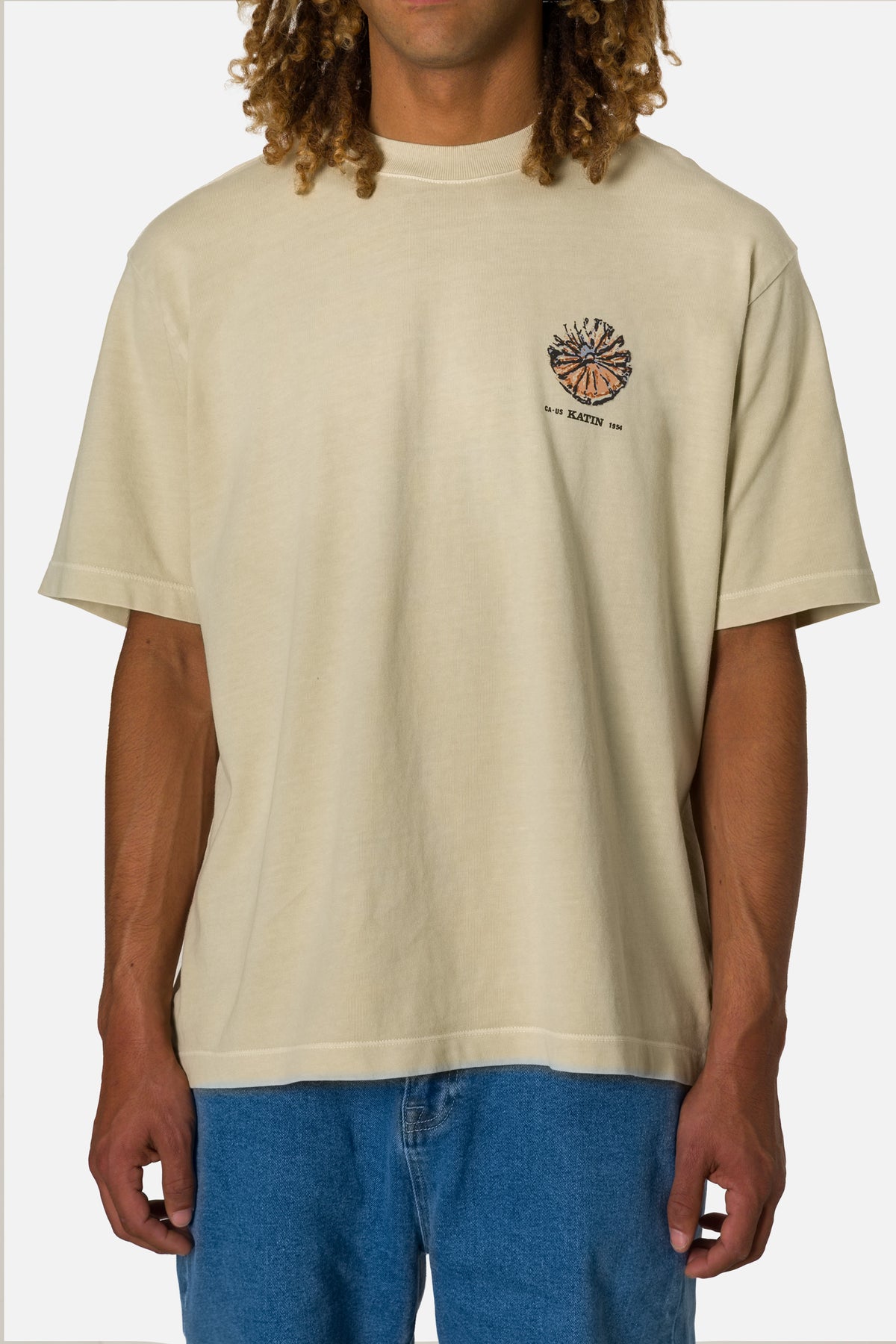 Man wearing a beige t-shirt with a logo on a white background