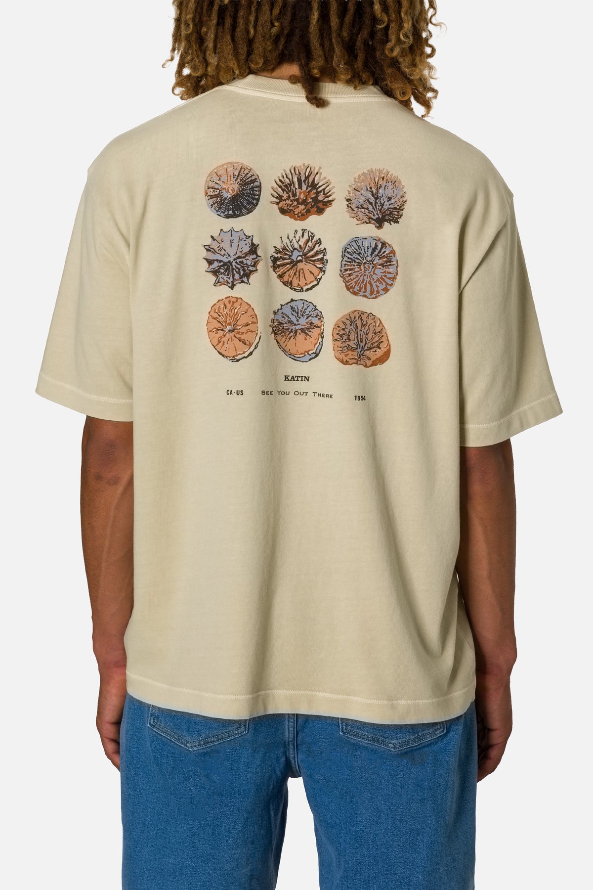 Person wearing a beige t-shirt with coral reef design on the back