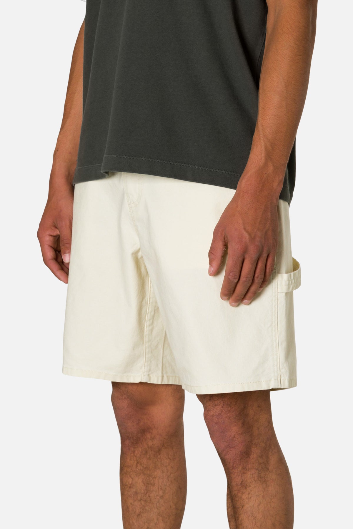 Side view person wearing off  white shorts and a black shirt on a plain background