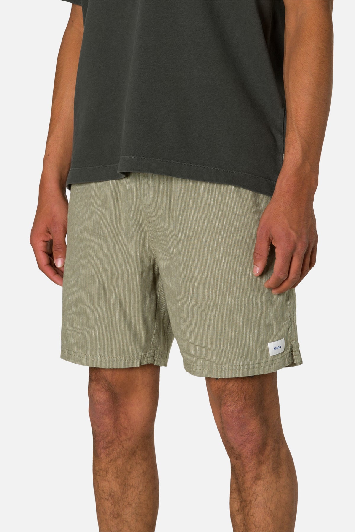 Person wearing olive green shorts and a dark shirt on a white background