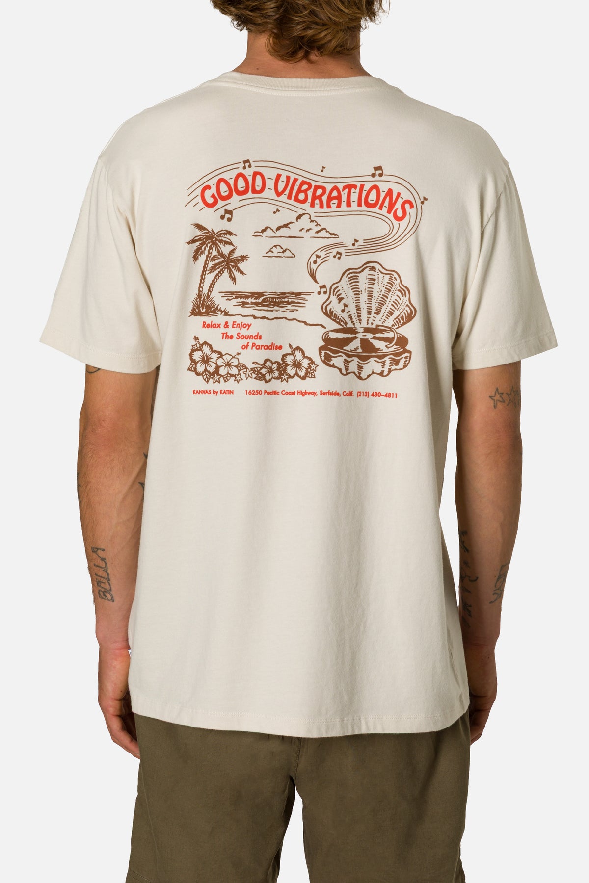 Person wearing a beige t-shirt with 'Good Vibrations' graphic design.