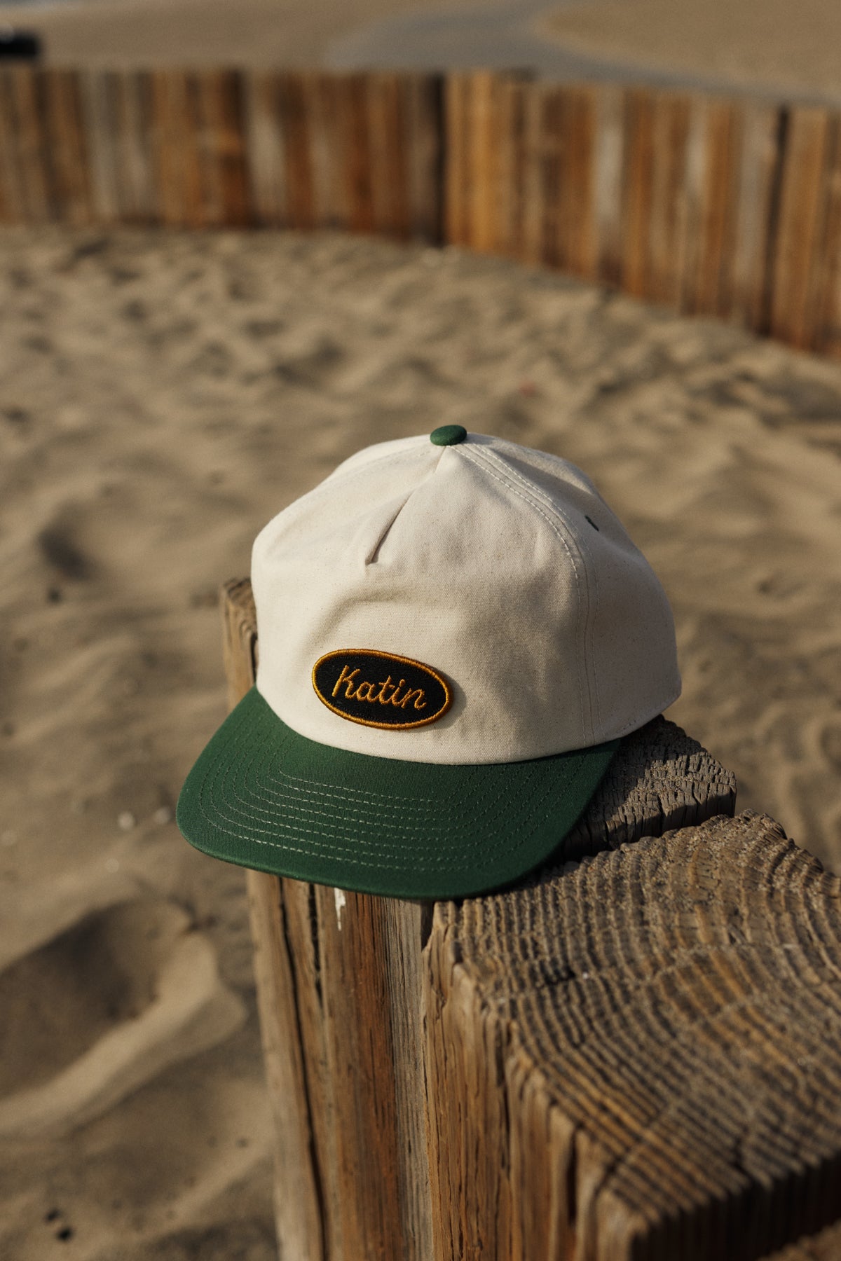 White and green cap with a logo on a wooden post at the beach