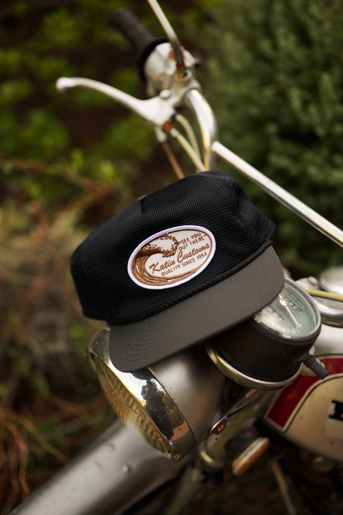 Black cap with a logo on a bicycle handlebar against a blurred green background