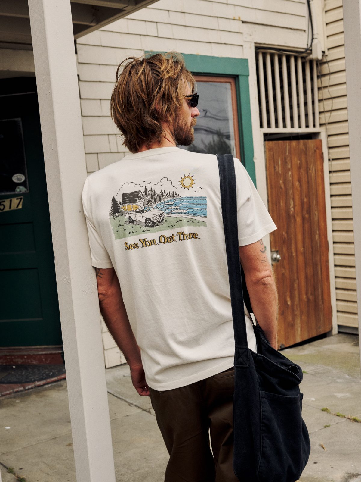 Katin Eureka Tee in Vintage White organic cotton, on model, back graphic of a surf truck at a coastal campsite, lifestyle #color_vintage white