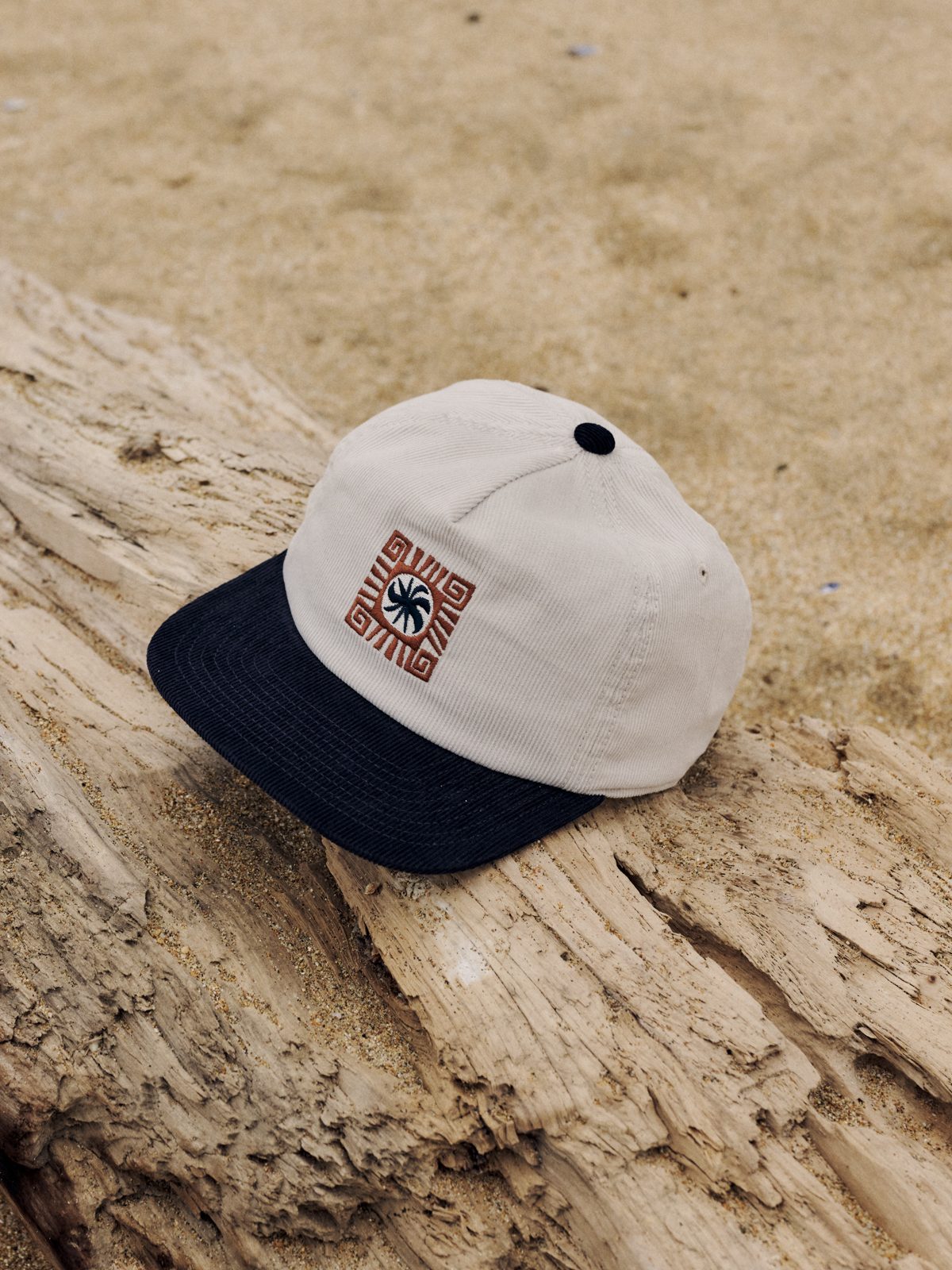 Katin Root Hat in Vintage White, corduroy five-panel with a contrast navy brim and embroidered sun graphic, on driftwood, lifestyle #color_vintage white