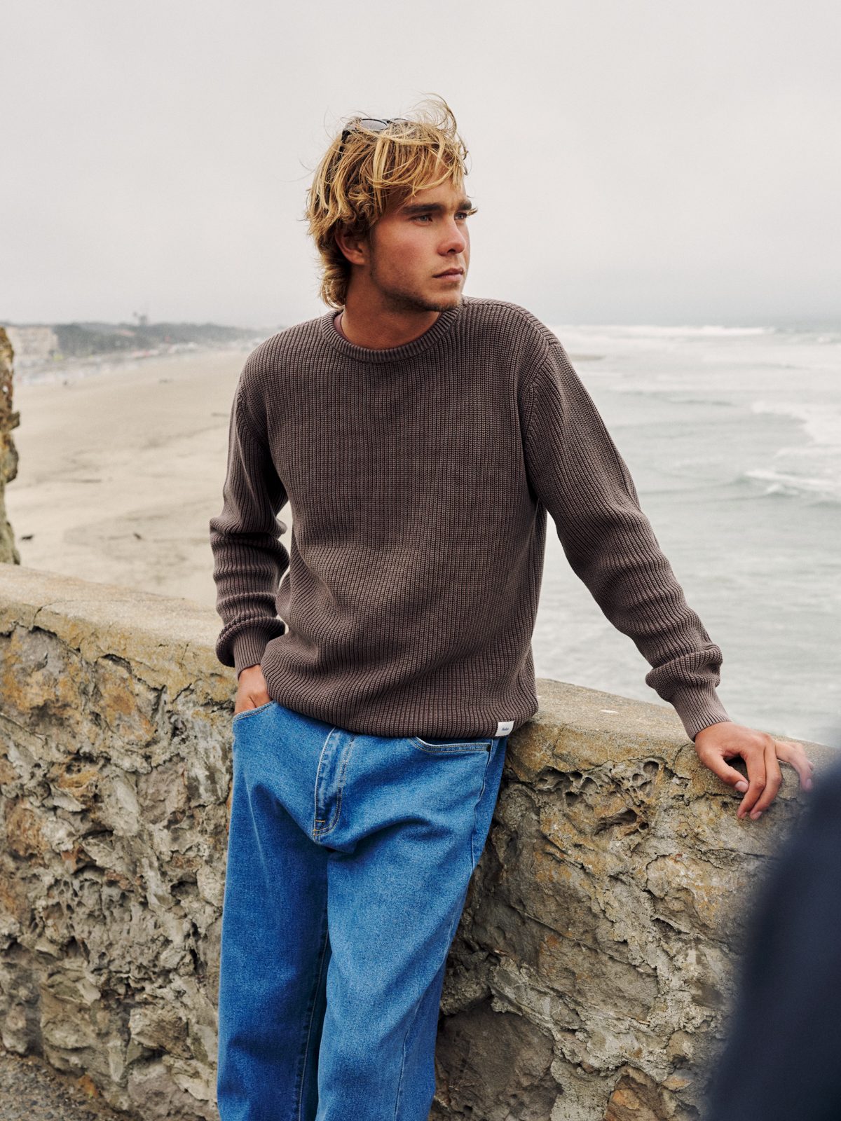 Katin Swell Sweater in French Roast, ribbed cotton knit with vintage wash, on model at a seawall, lifestyle #color_french roast