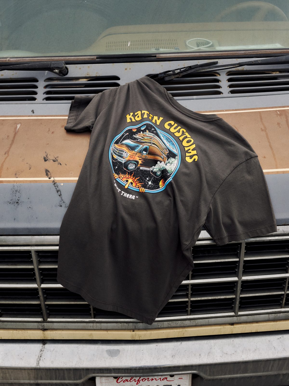 Katin Vantasy Tee in Lead organic cotton, laid on a vintage truck hood, back “Katin Customs” van-in-space graphic, lifestyle #color_lead vintage wash